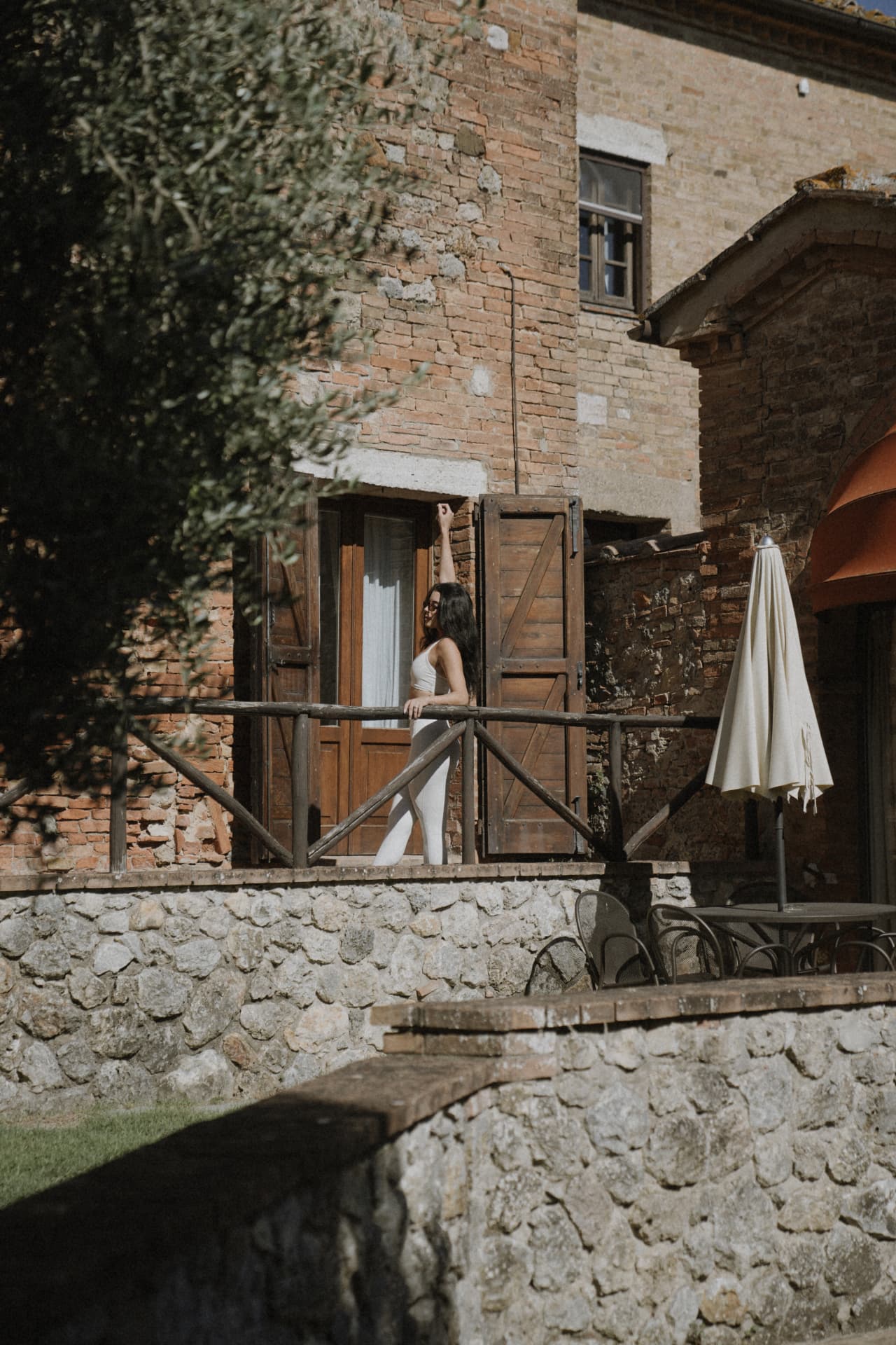 A woman stretching on a sunlit stone terrace outside the villa