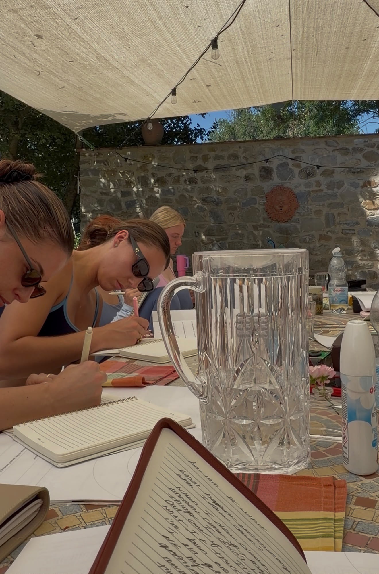 A small circle of women reading and journalling in a sunlit stone villa room