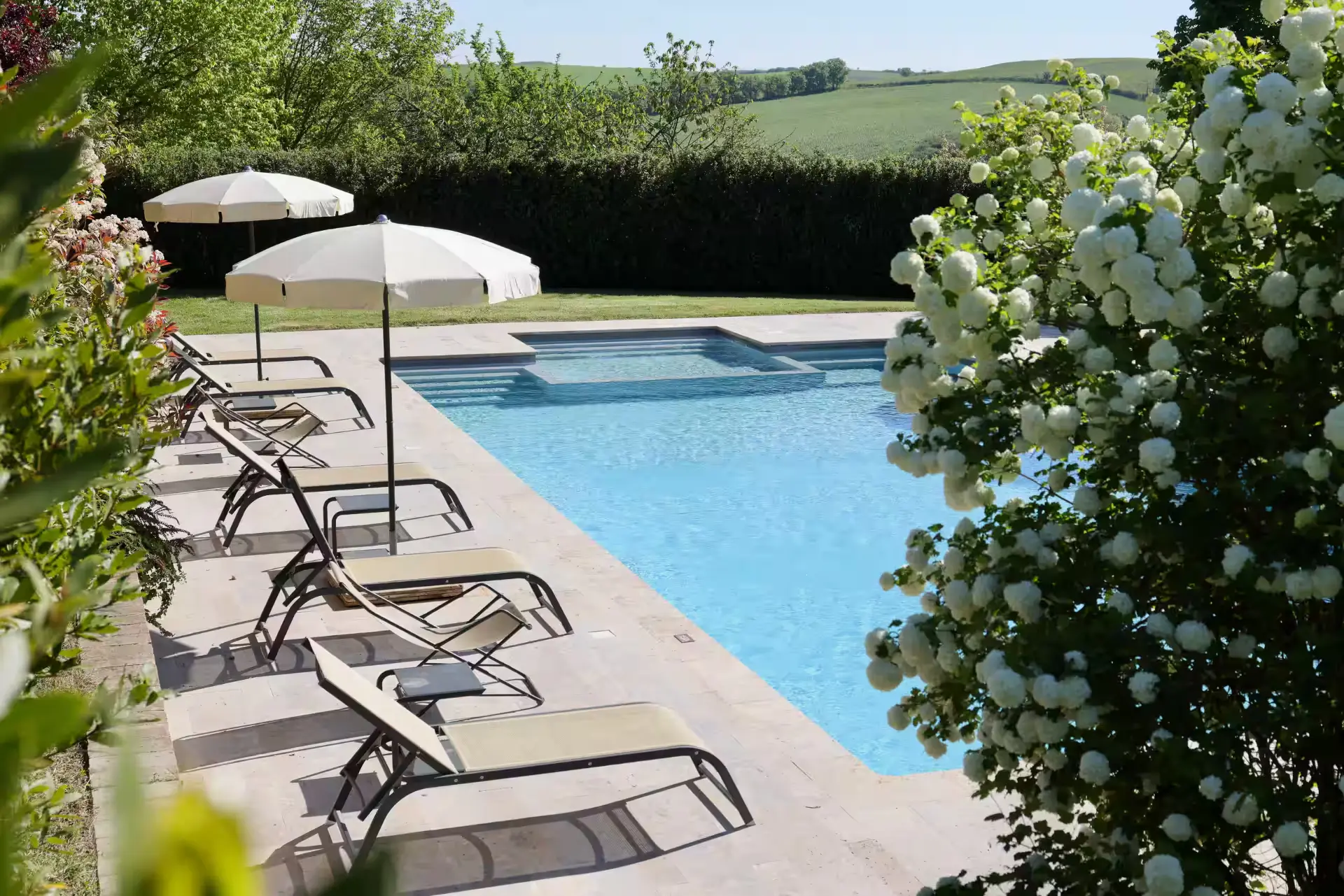 Loungers and parasols beside the villa pool with hills beyond