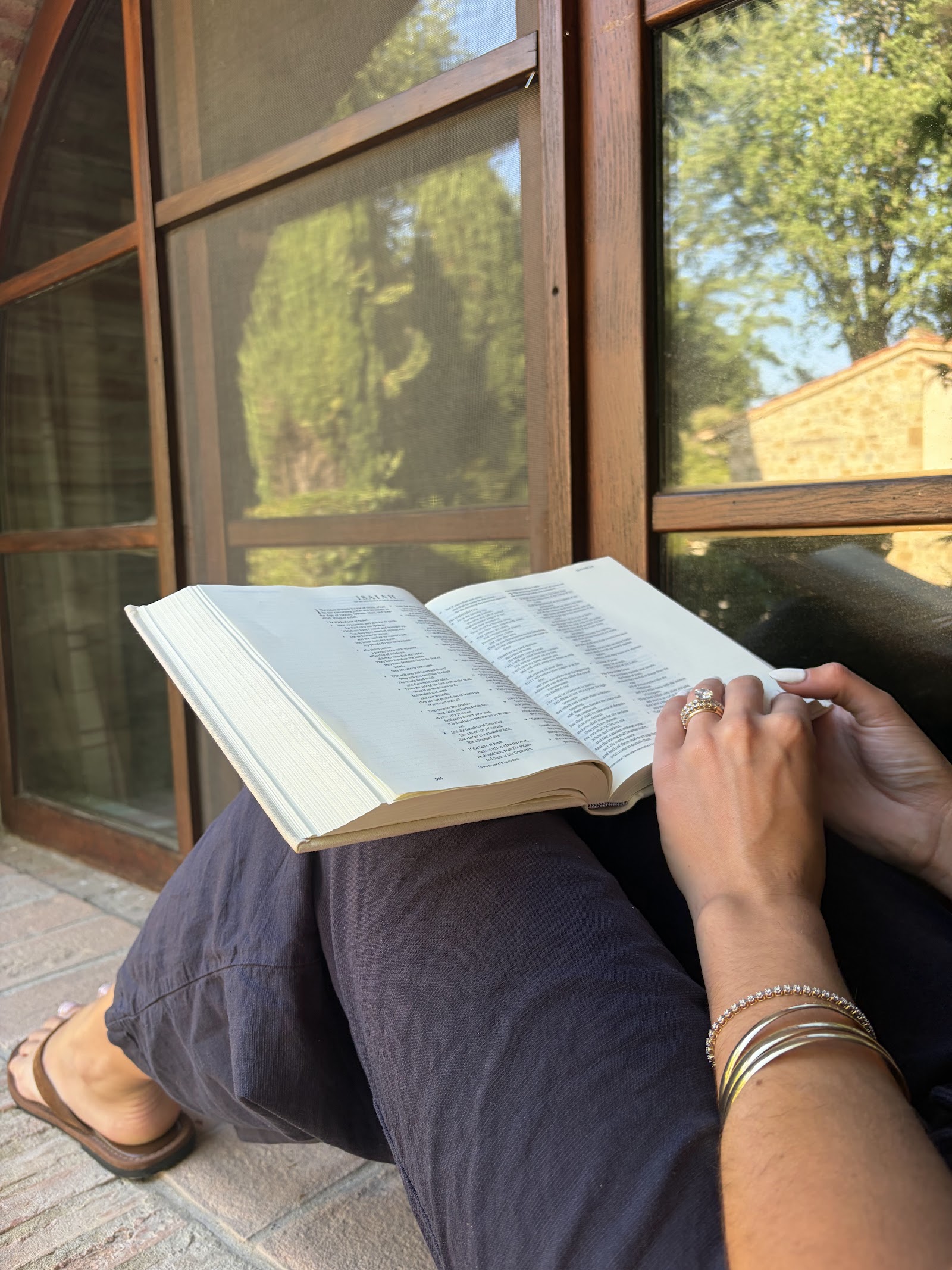 A woman reading by a sunlit villa window