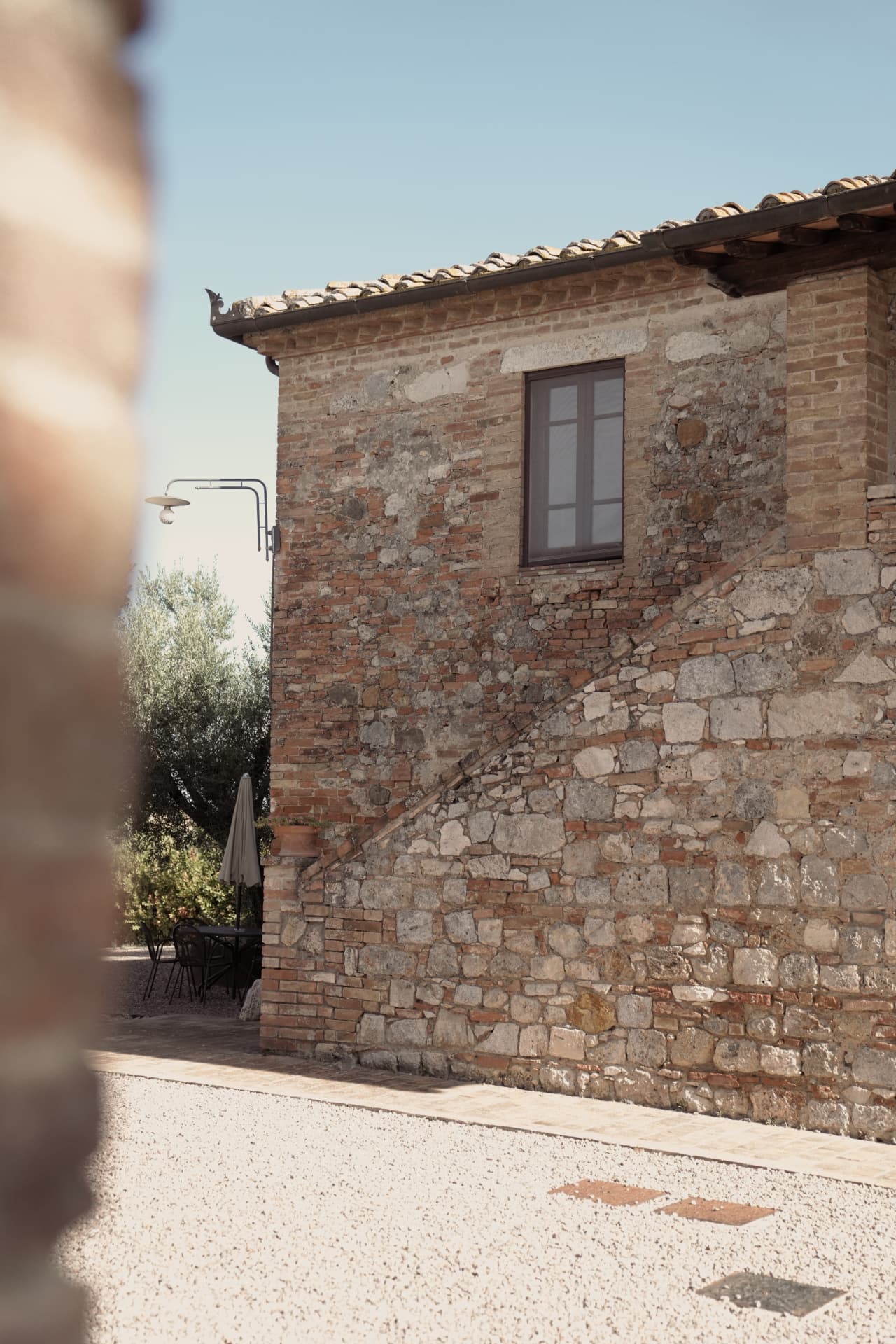 The villa's brick and stone facade with an external staircase and a gravel courtyard