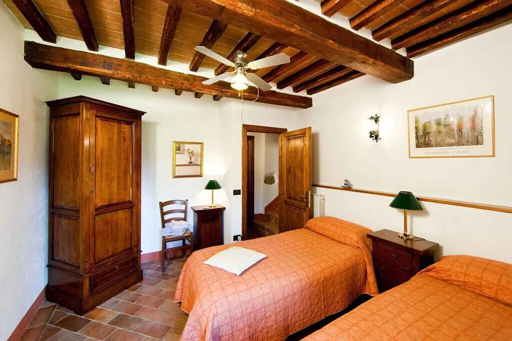A twin bedroom with beamed ceilings and terracotta floors